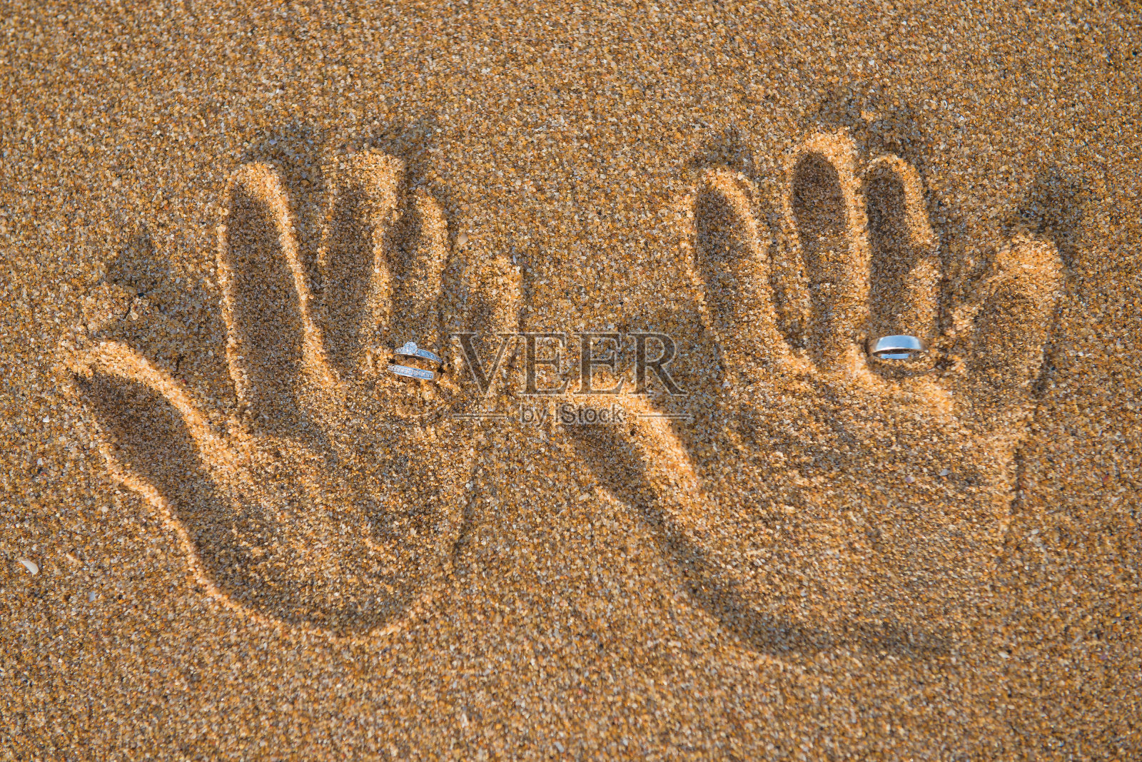 手拿结婚戒指放在沙滩上照片摄影图片