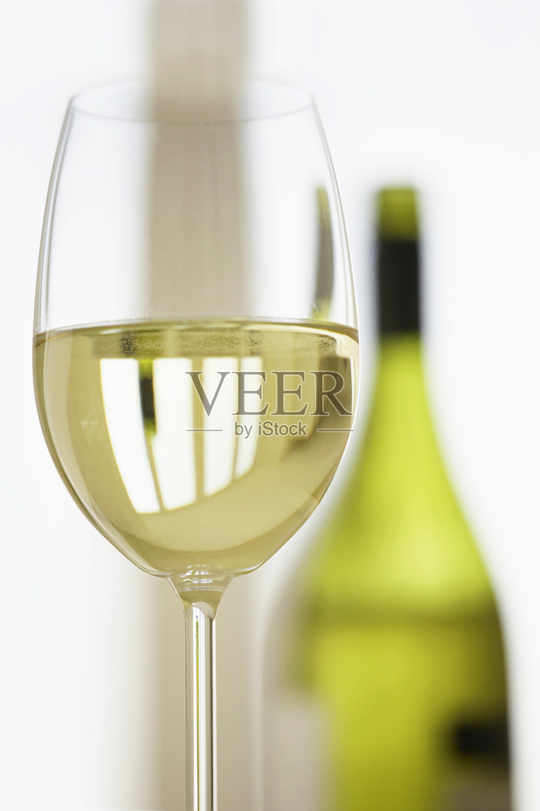 一杯白葡萄酒，后面是酒瓶。照片摄影图片