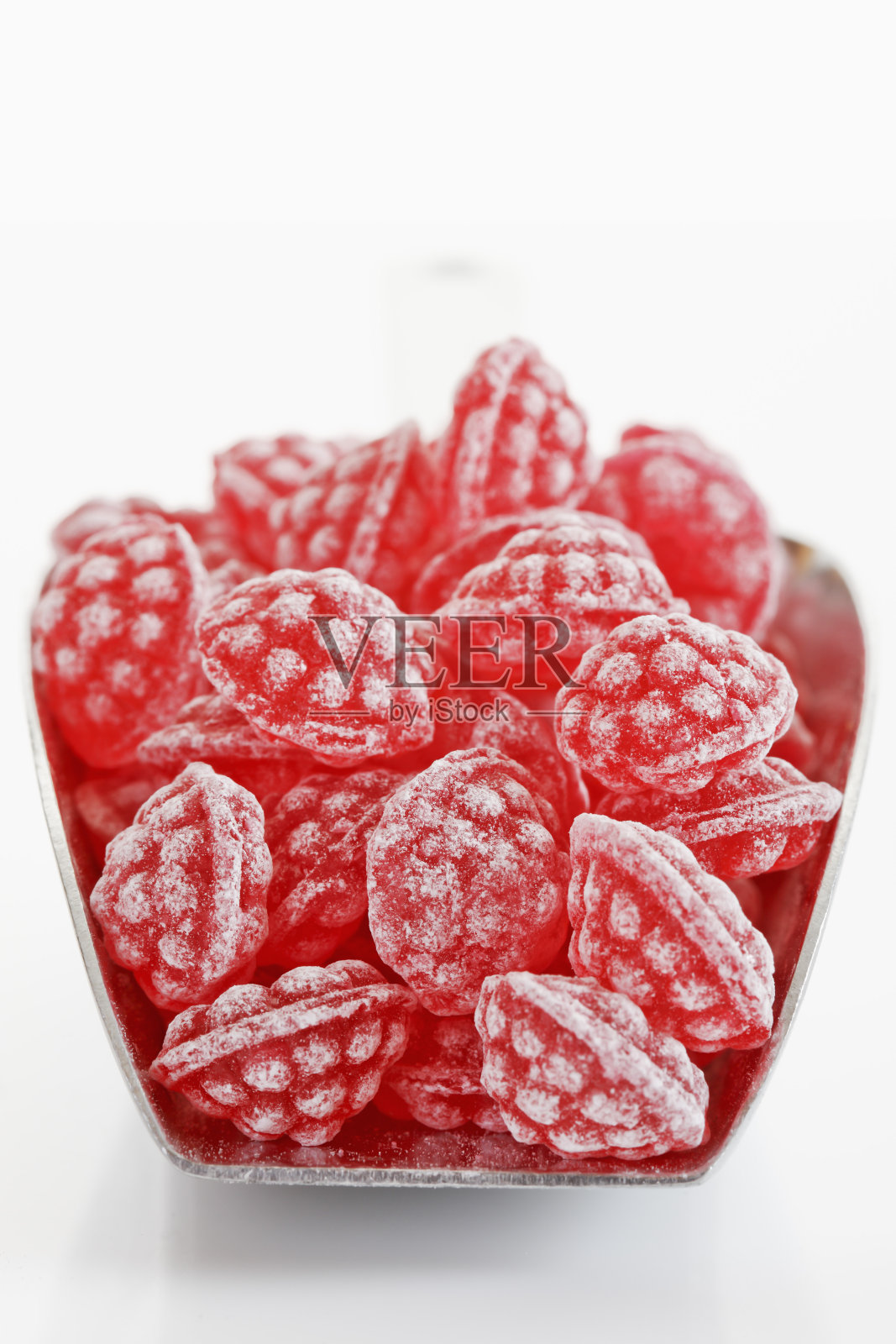 在白色背景的金属勺覆盆子糖果照片摄影图片