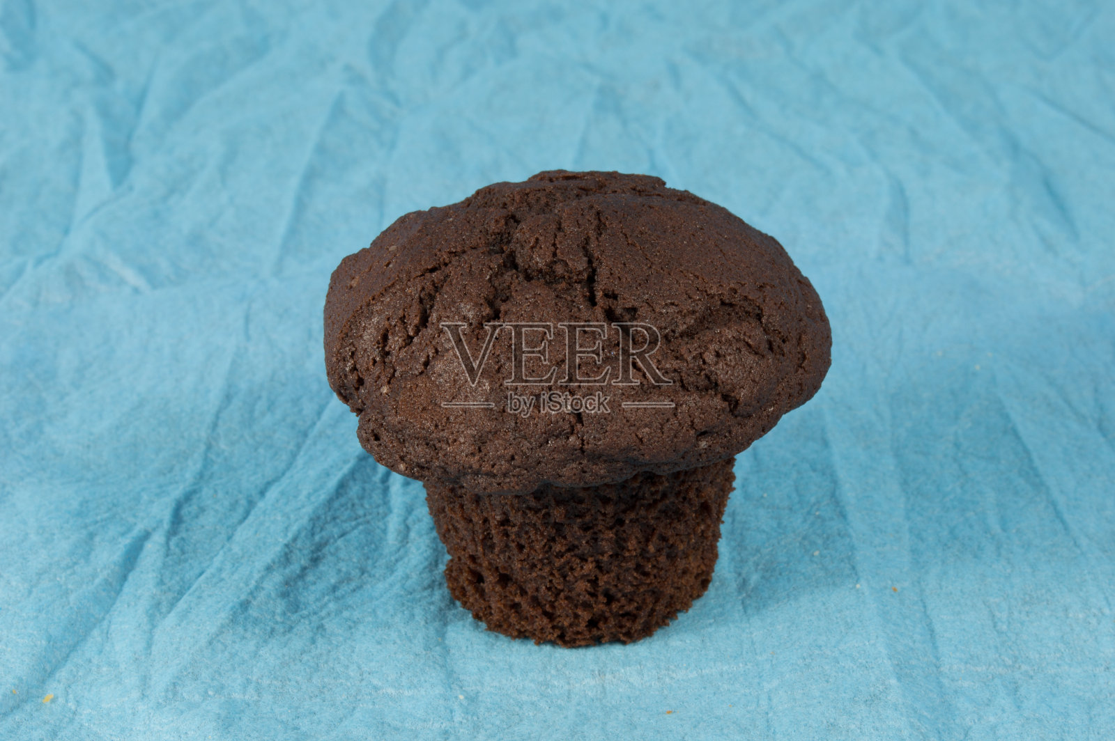 一个浅蓝色背景的棕色巧克力松饼照片摄影图片