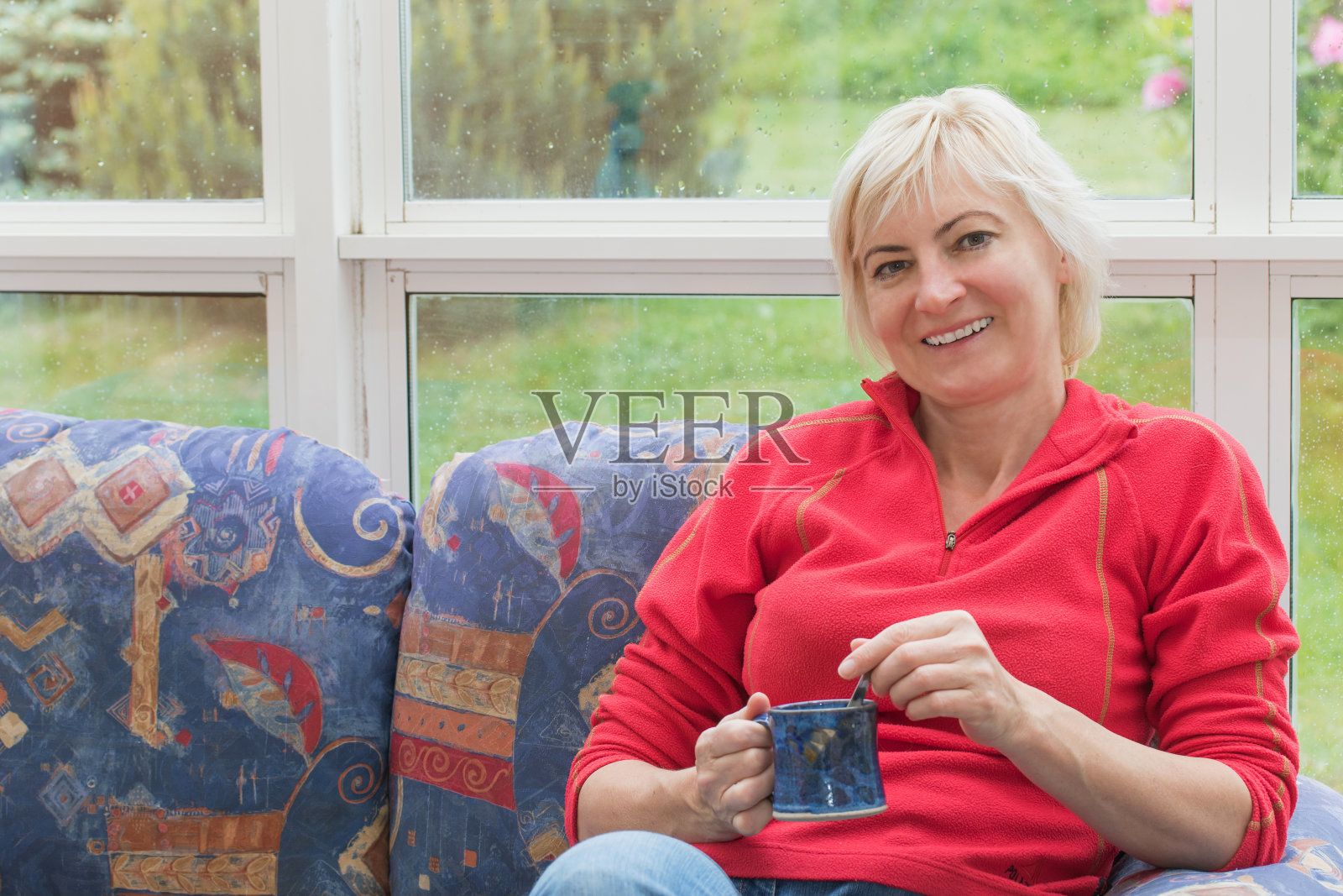 面带微笑的金发中年妇女正在沙发上休息照片摄影图片