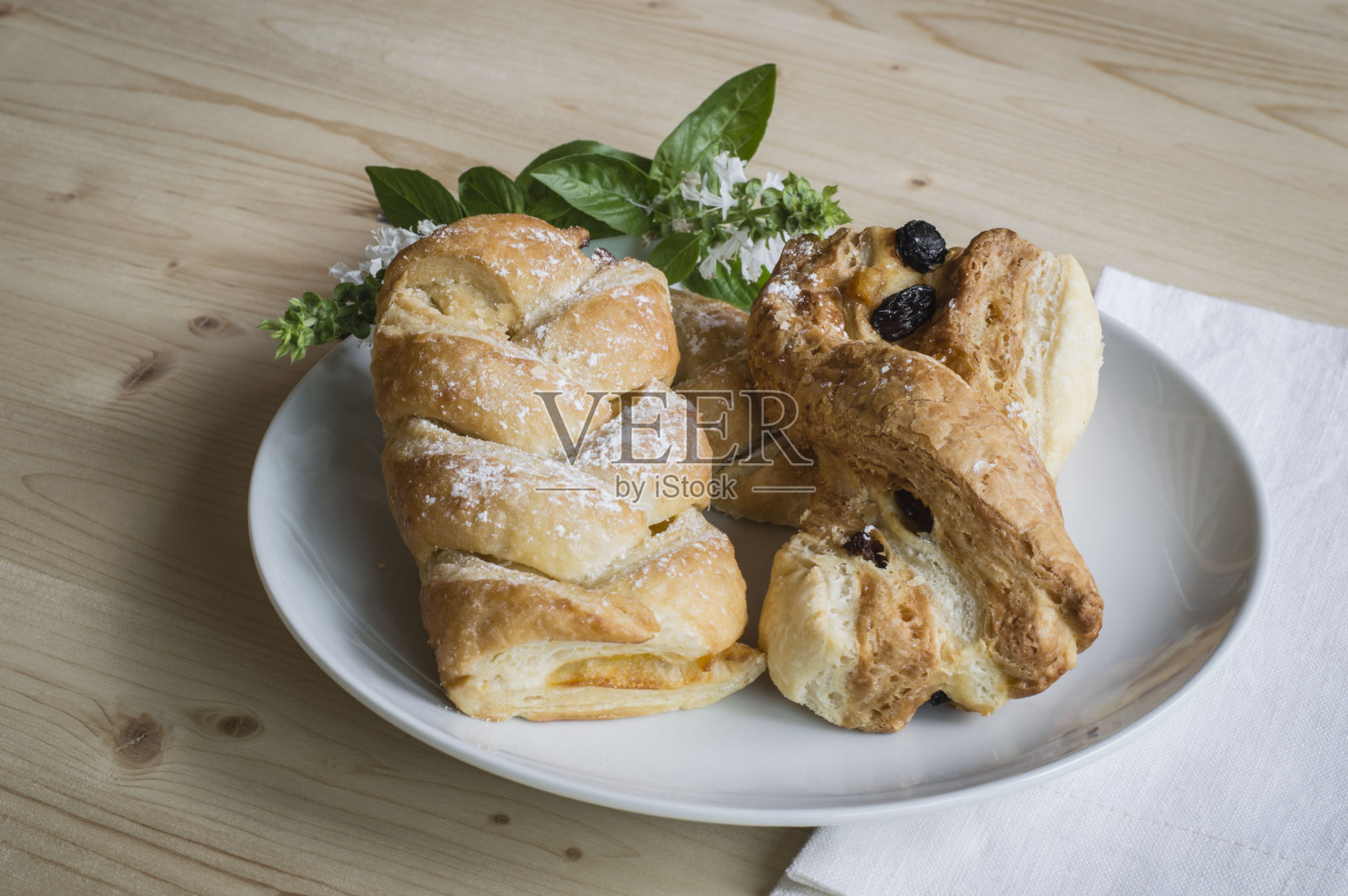 白盘子里放着糕点，木桌上放着小花照片摄影图片