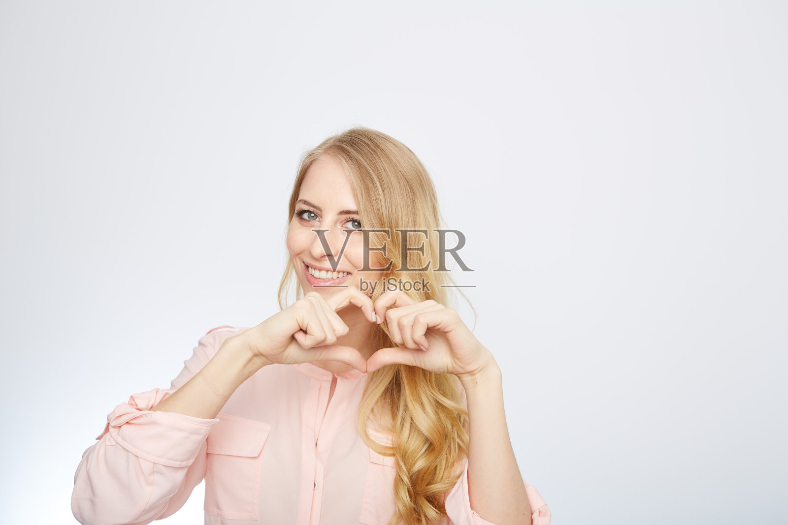 年轻的金发女人做了一个心形的象征照片摄影图片