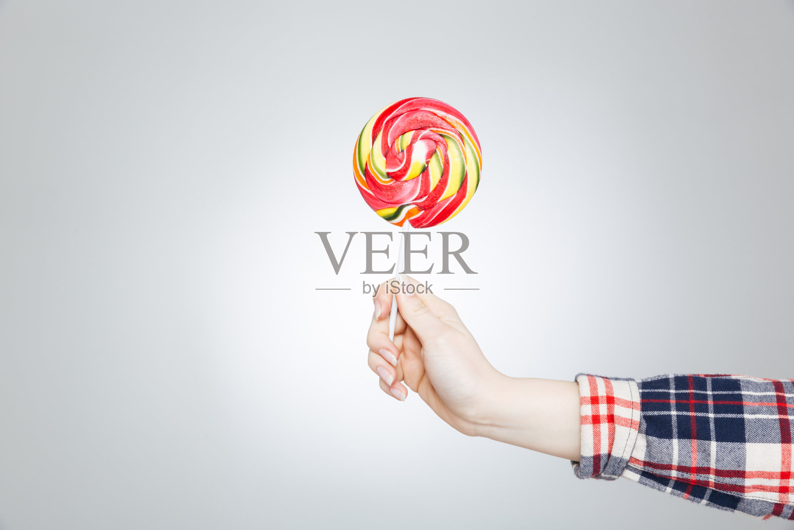 手里拿着五颜六色的棒棒糖的格子衬衫照片摄影图片