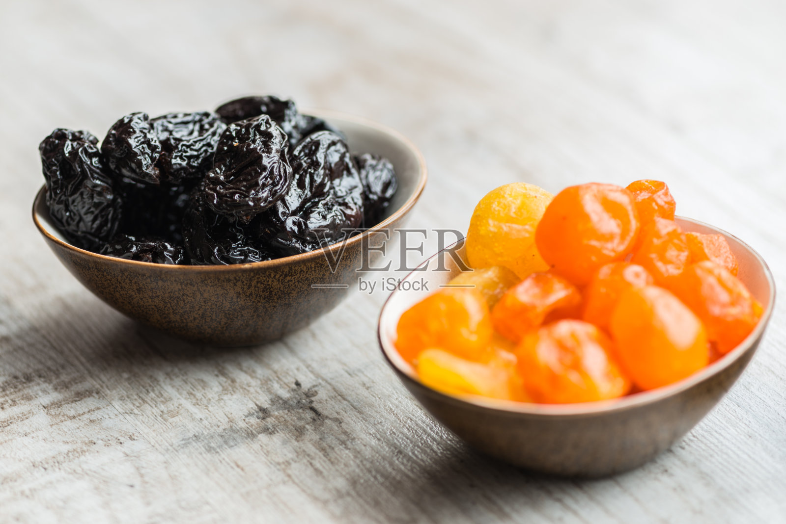 两个盘子和干果在木背景:干桔子和西梅干照片摄影图片