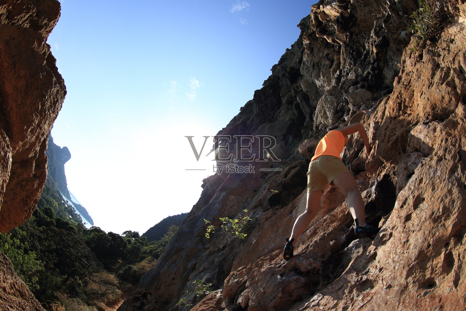 一名年轻女子攀岩者正在海边的悬崖上攀岩照片摄影图片