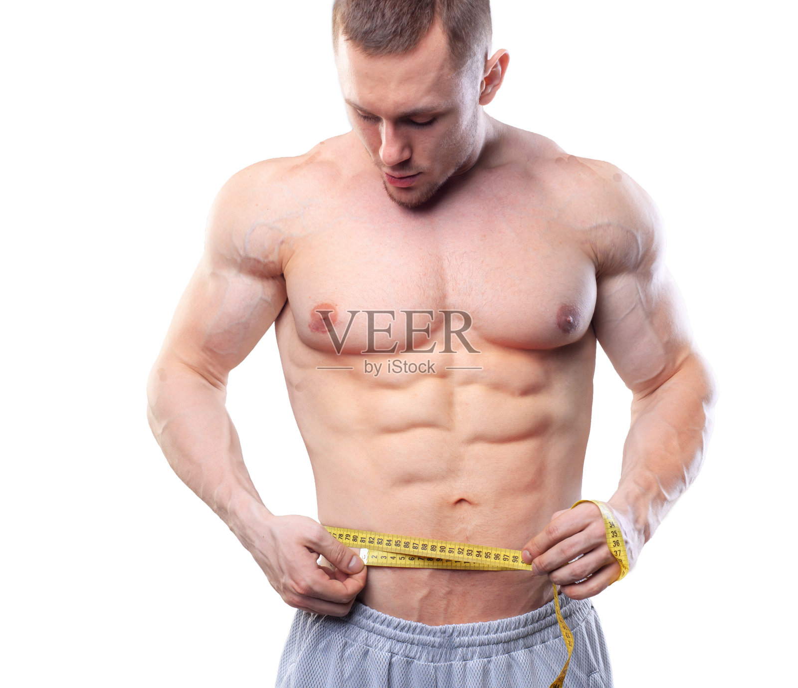 肌肉男用卷尺测量腰围照片摄影图片