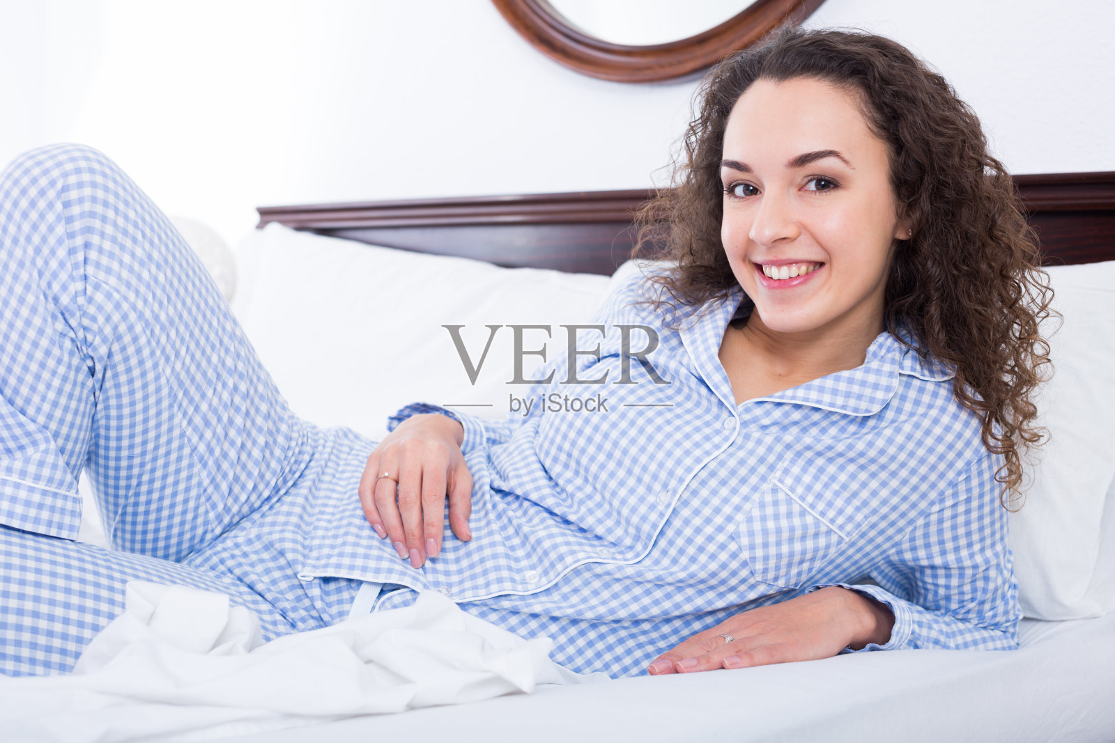 黑发女性懒洋洋地躺在床上，面带微笑照片摄影图片