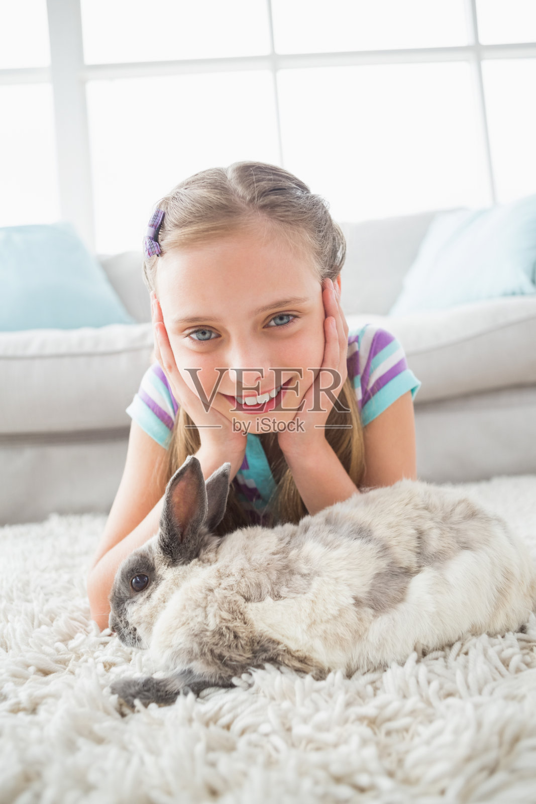 快乐的女孩和兔子躺在客厅的地毯上照片摄影图片