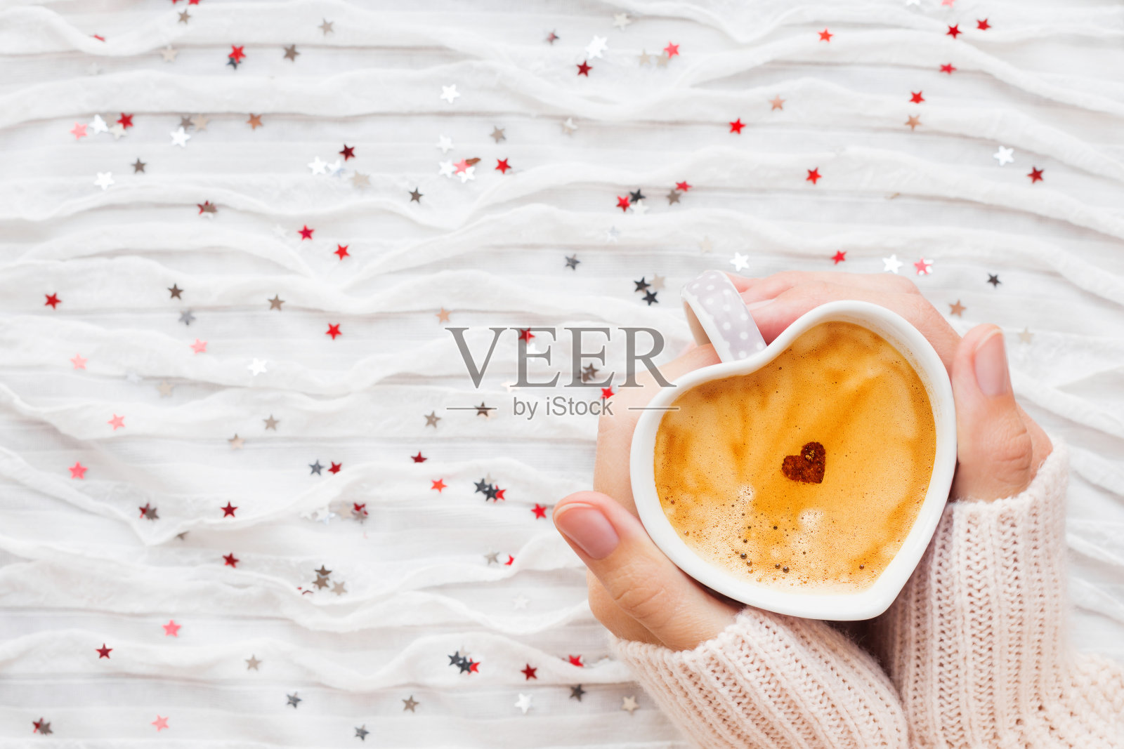 女人拿着一杯肉桂心的热咖啡。照片摄影图片