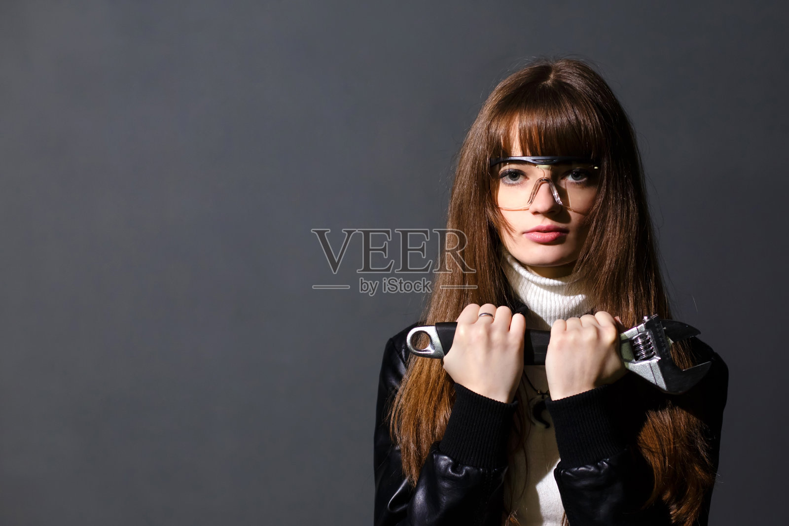 戴着安全眼镜，带着活动扳手的女孩照片摄影图片