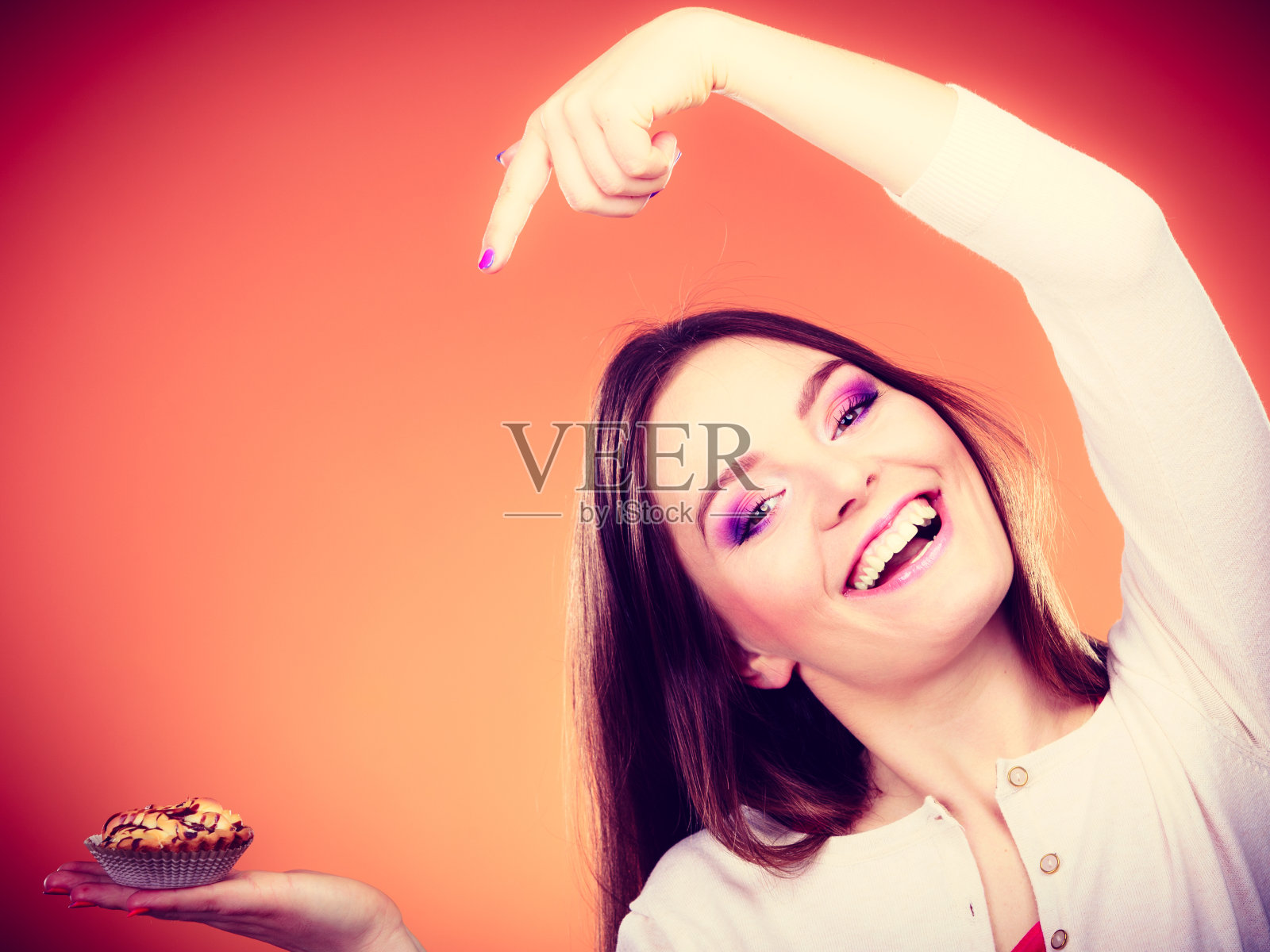 微笑的女人拿着蛋糕用手指指着照片摄影图片