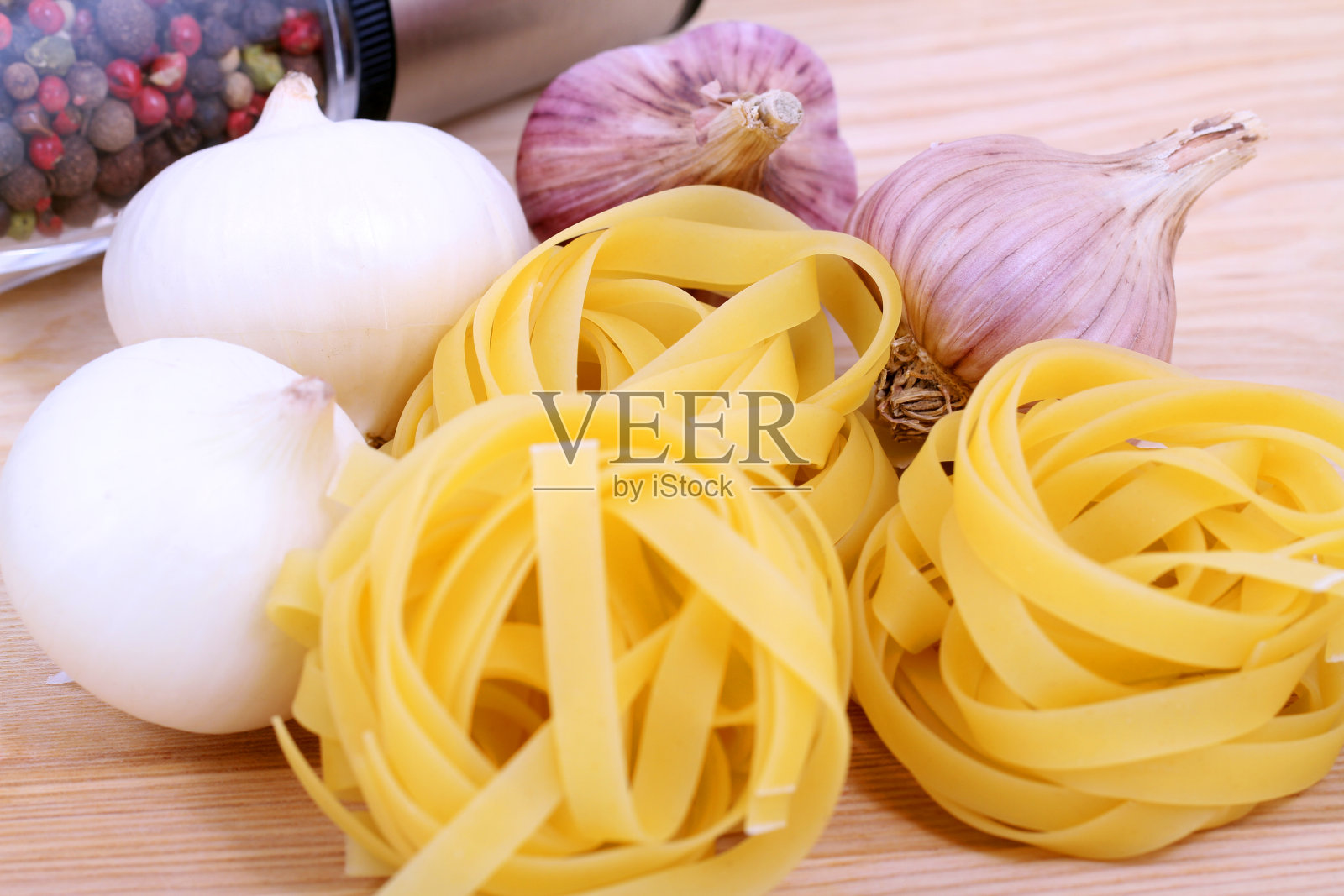 木盘上放意大利面、洋葱、大蒜和胡椒照片摄影图片