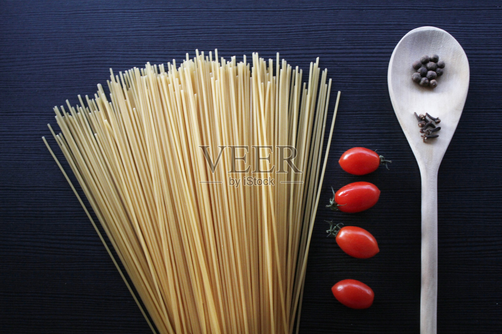 木桌上的意大利面、香料和圣女果照片摄影图片