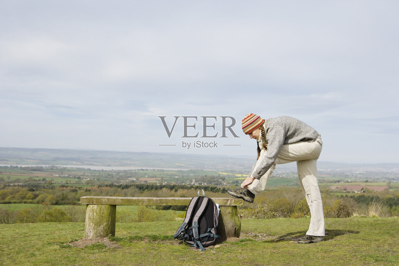 女徒步旅行者在公园长凳上系鞋带照片摄影图片