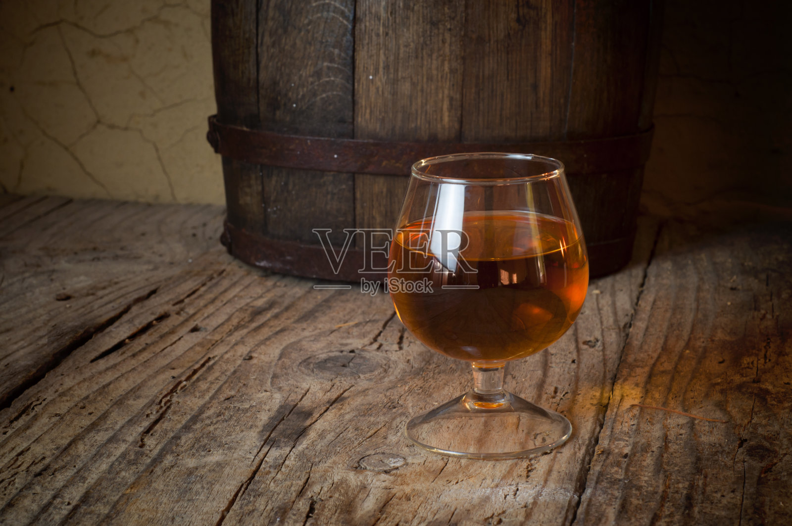 在酒窖里放着一杯白兰地，还有堆放着的旧酒桶照片摄影图片
