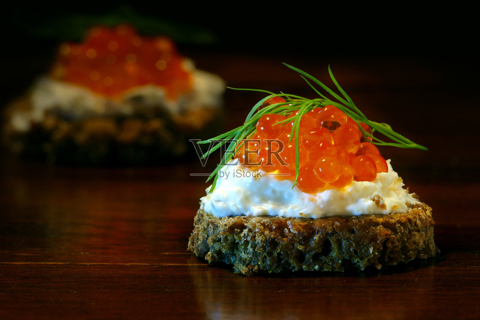 用红鱼子酱和莳萝装饰的开胃小菜放在深色的木头上照片摄影图片