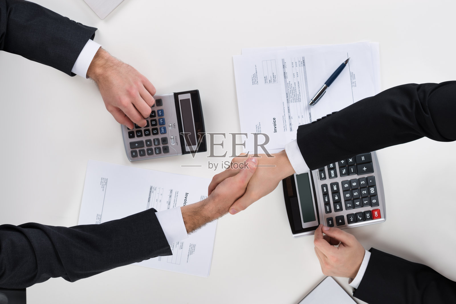 商务人士在桌前计算财务时握手照片摄影图片