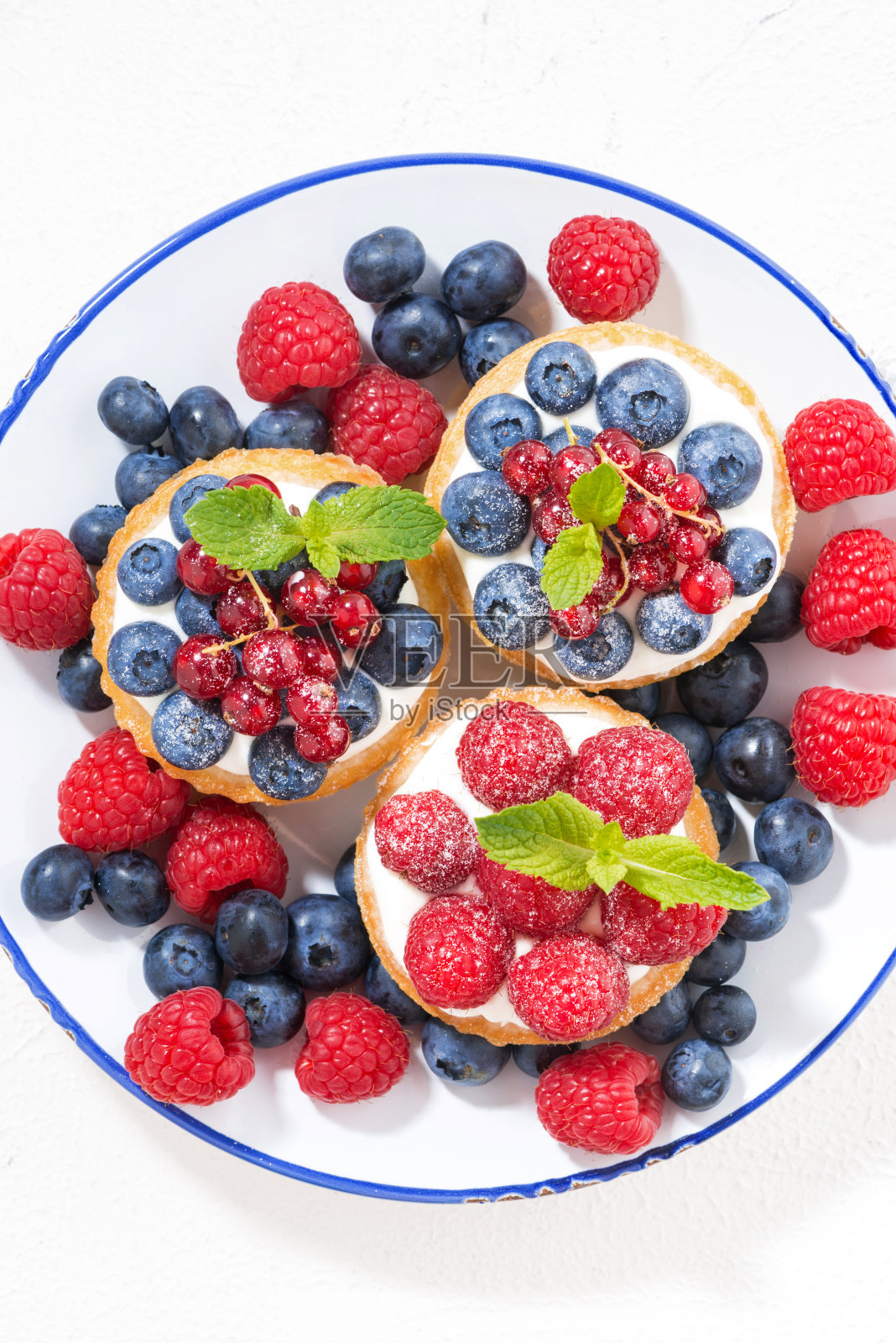 迷你蛋糕与甜奶油和浆果盘，垂直照片摄影图片