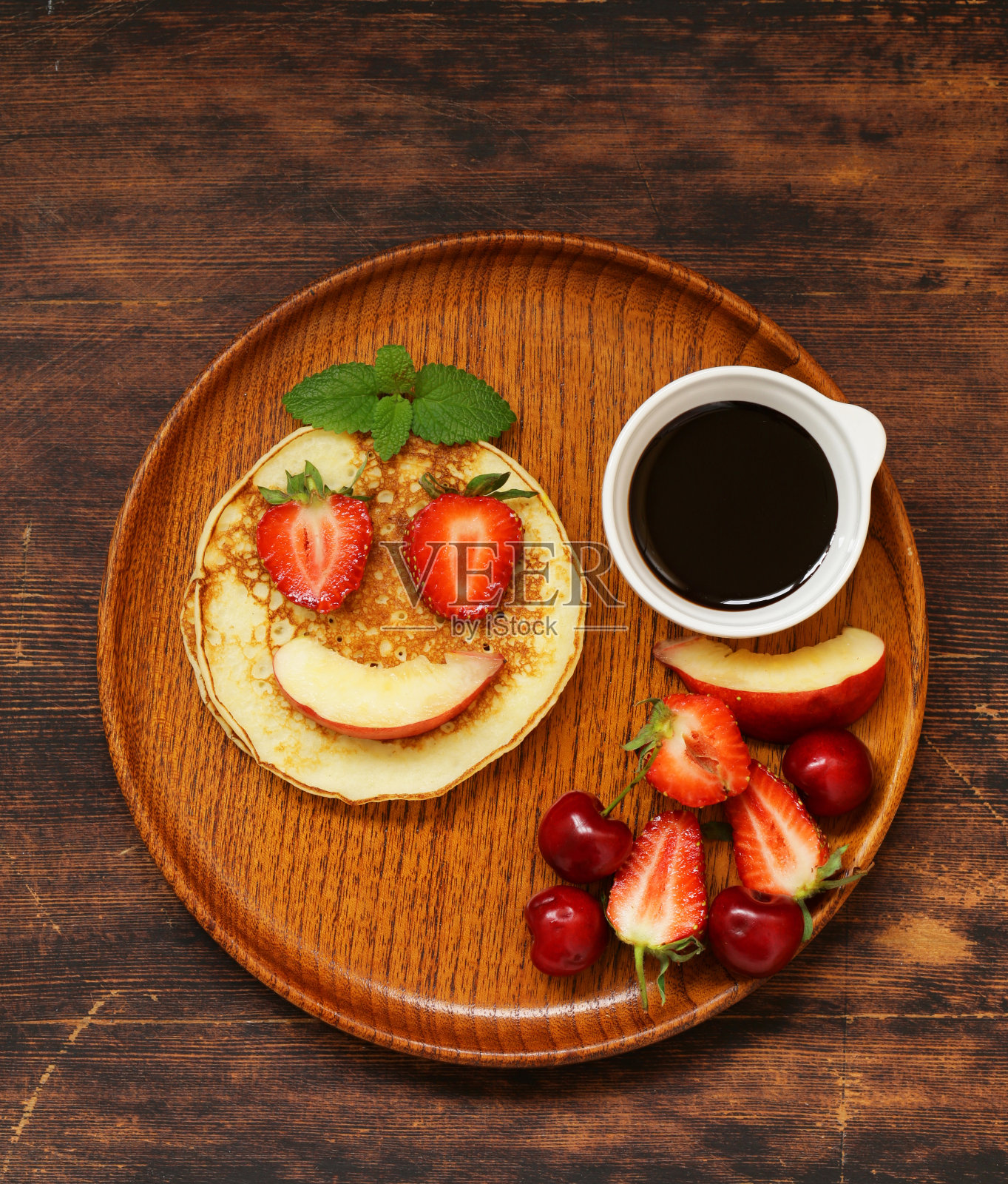 早餐煎饼配浆果(草莓，樱桃，香蕉)，滑稽的脸照片摄影图片