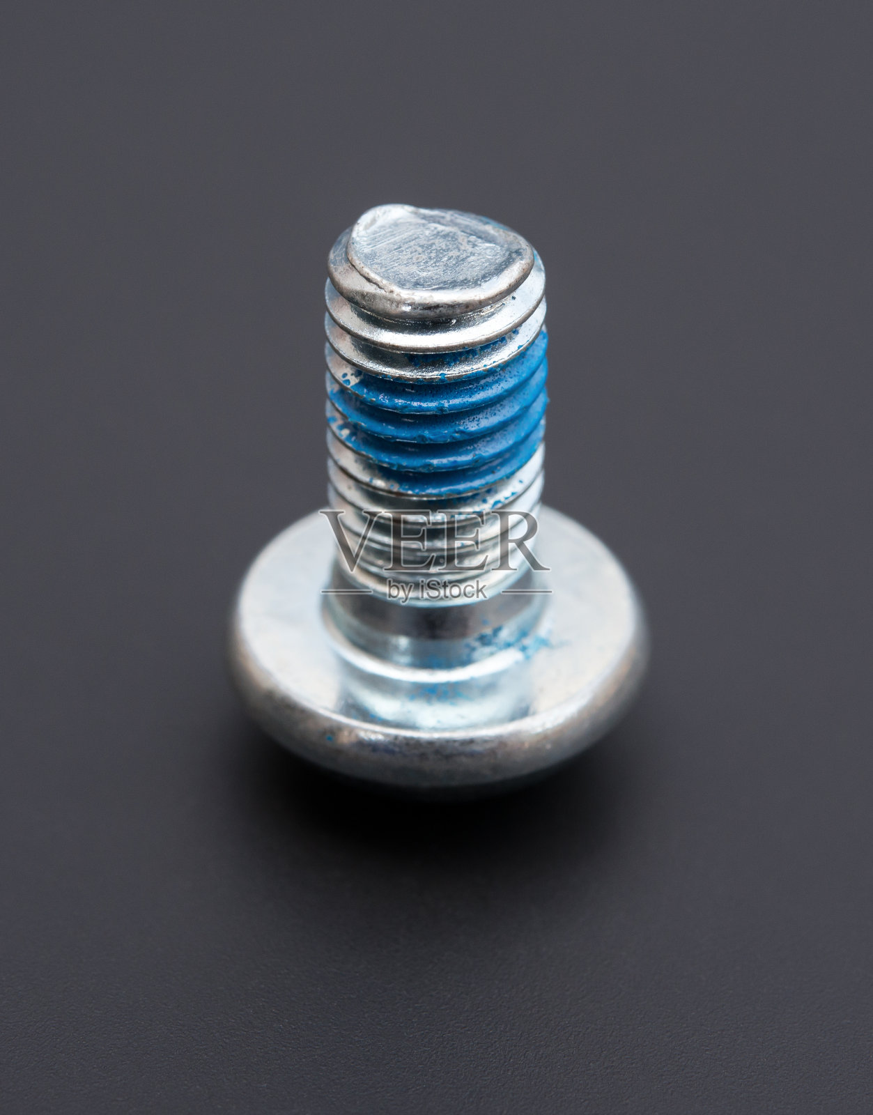 用蓝色胶水在黑色背景上的圆头螺栓照片摄影图片