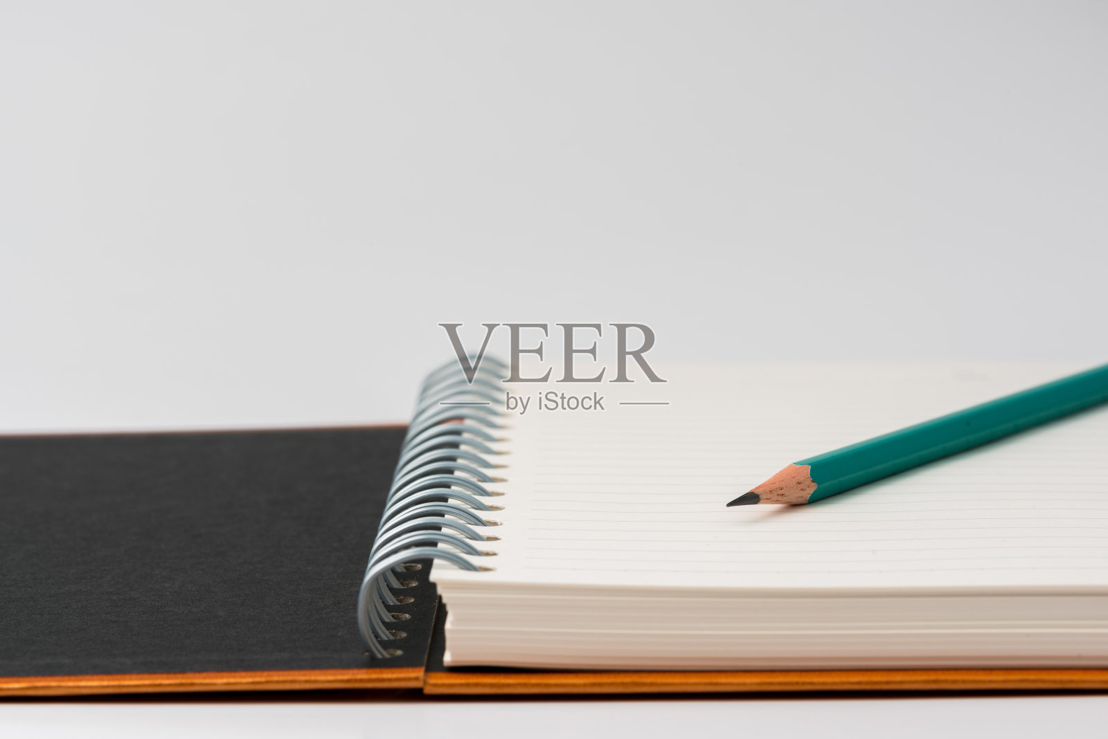 绿色铅笔在戒指簿上。照片摄影图片