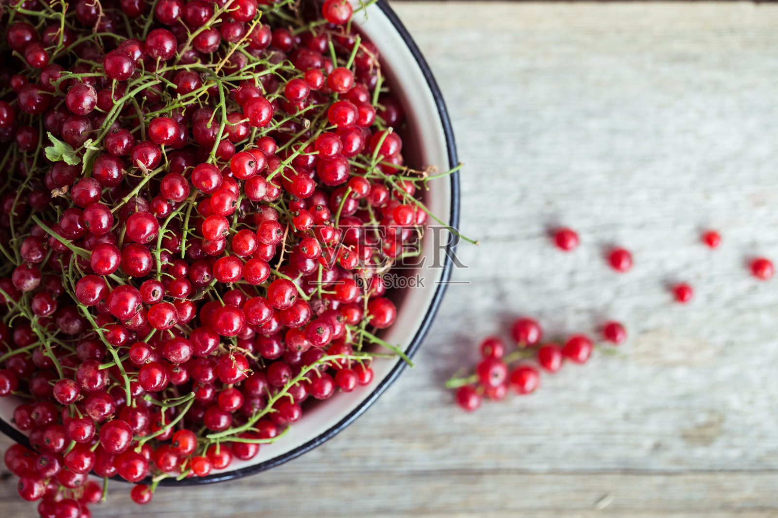 木制背景上的搪瓷锅里有红醋栗照片摄影图片