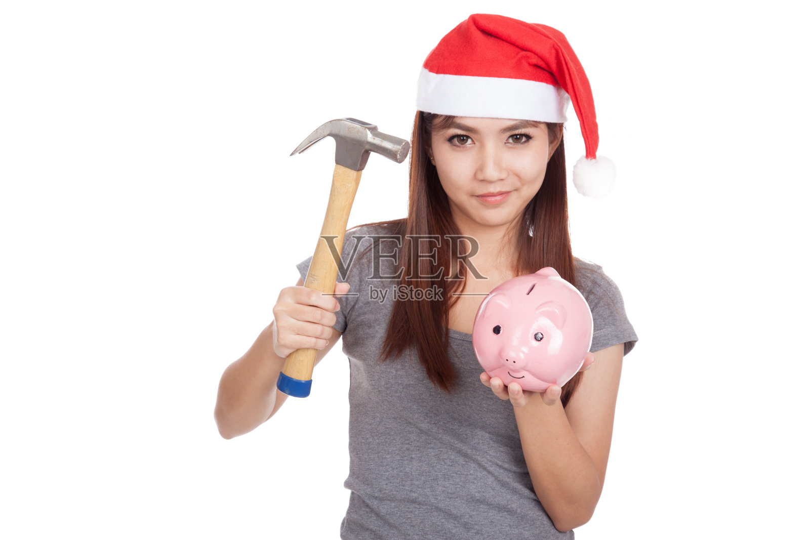 亚洲女孩与圣诞老人帽子握锤子和小猪银行照片摄影图片