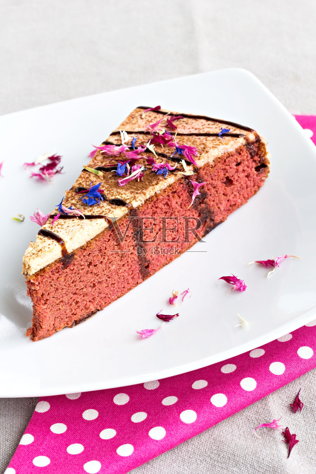 一片漂亮的红色甜菜根蛋糕，上面点缀着奶油照片摄影图片