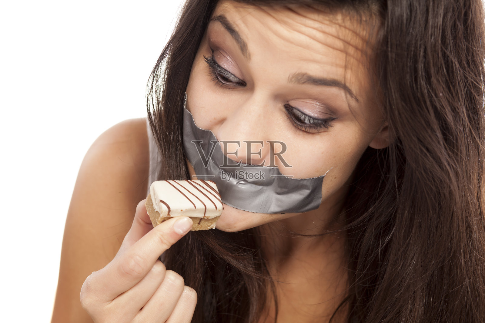 贪婪的女孩用胶带粘着她的嘴拿着蛋糕照片摄影图片