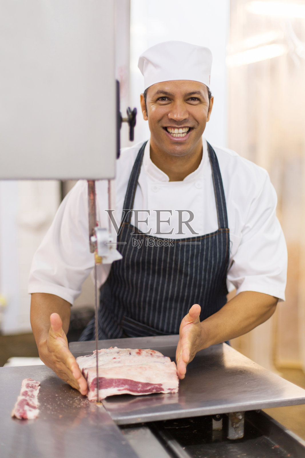 成年男性屠夫在带锯上切肉照片摄影图片