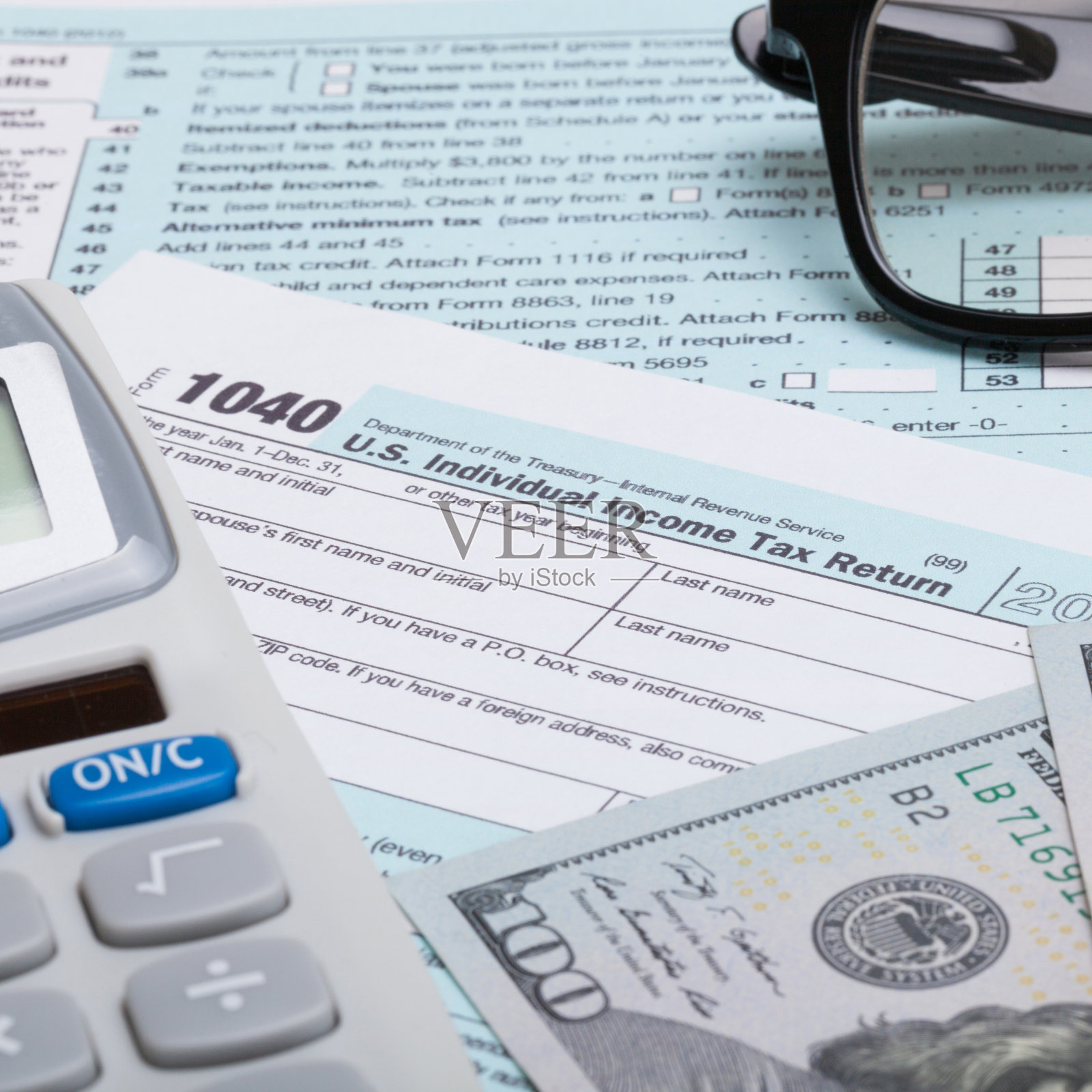 1040税表，计算器，眼镜和美元-接近照片摄影图片