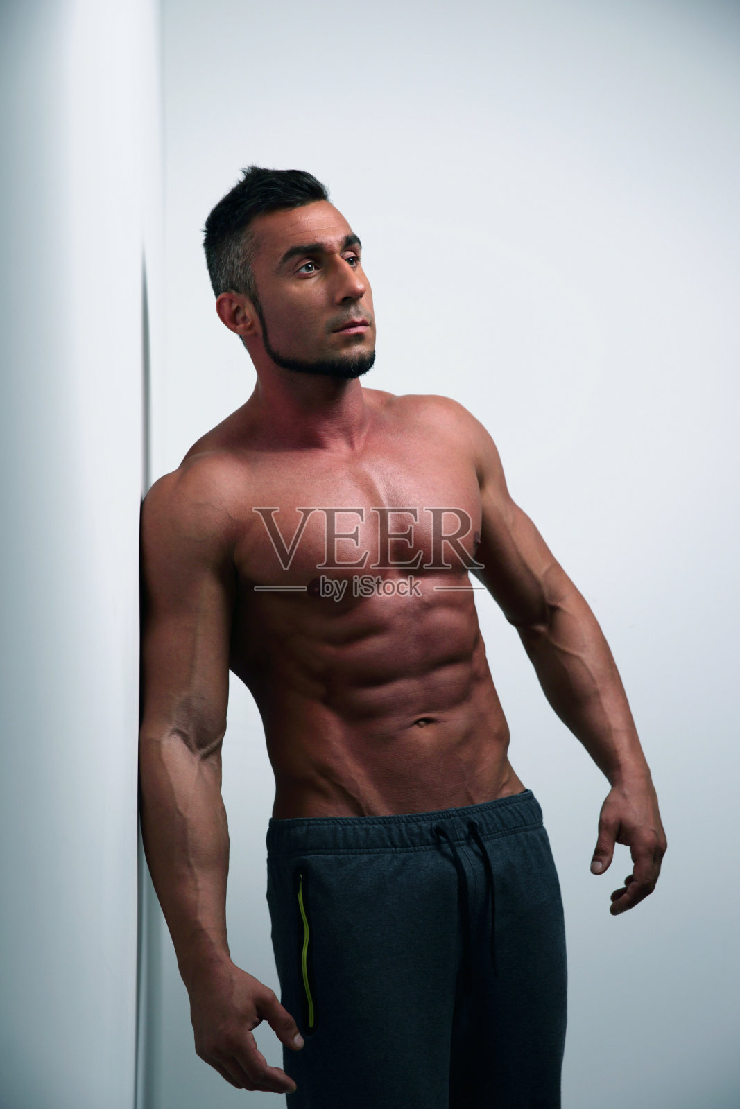 靠在墙上的肌肉男照片摄影图片