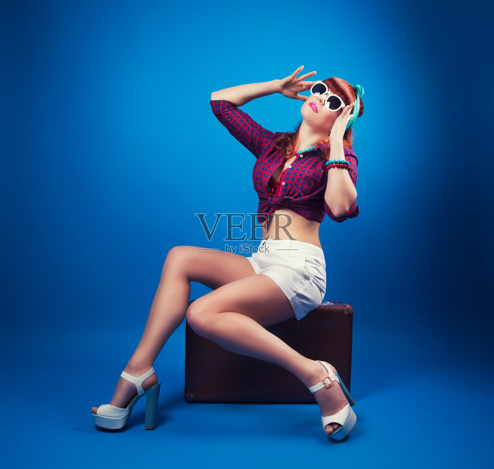 漂亮的海报女郎摆姿势与复古手提箱对抗蓝色照片摄影图片