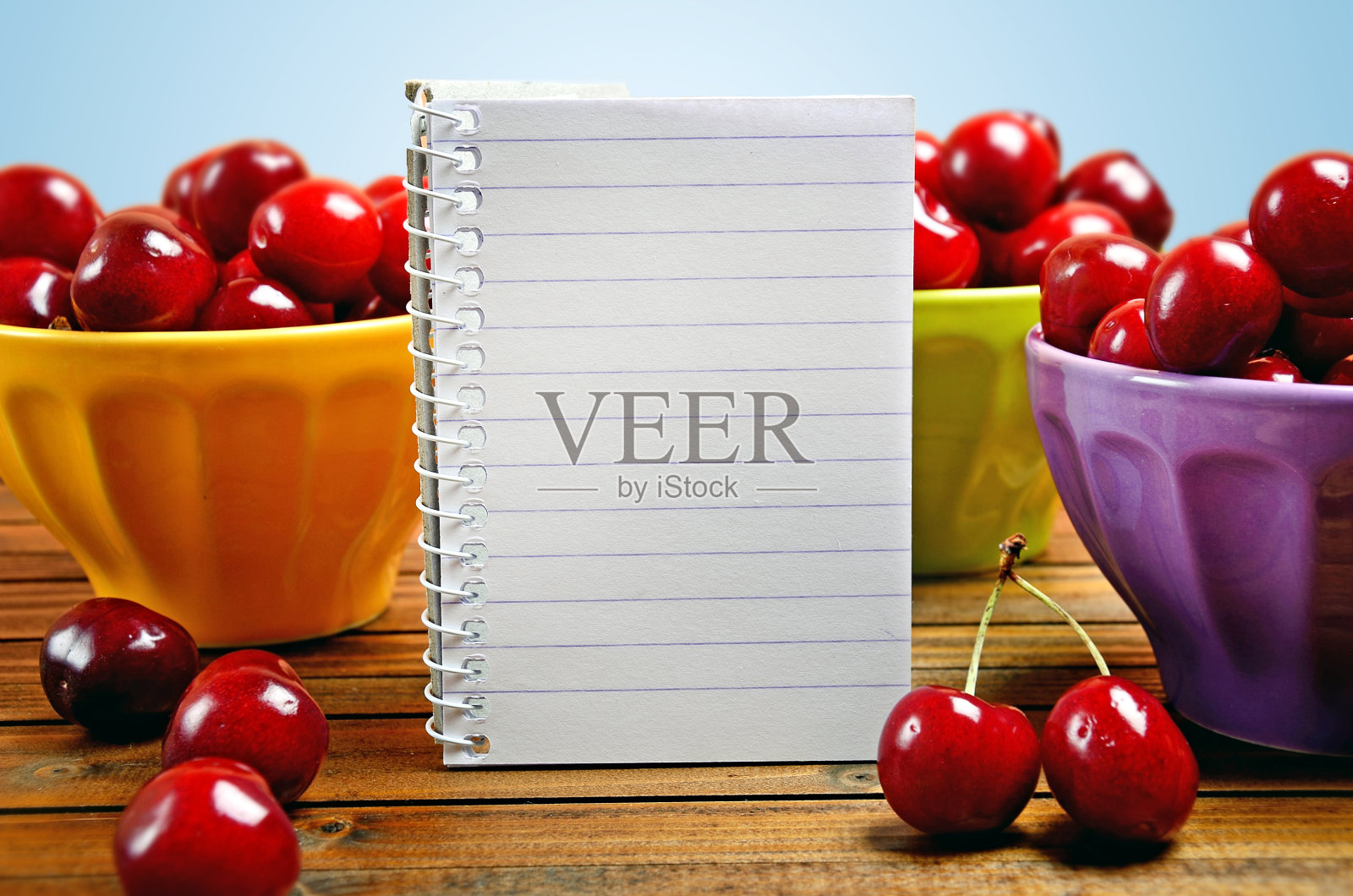 笔记本和五颜六色的樱桃碗照片摄影图片