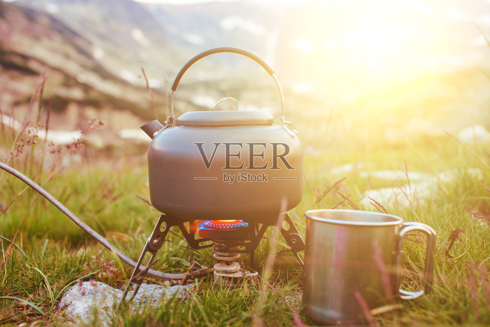 草地上的露营茶壶和帽子照片摄影图片