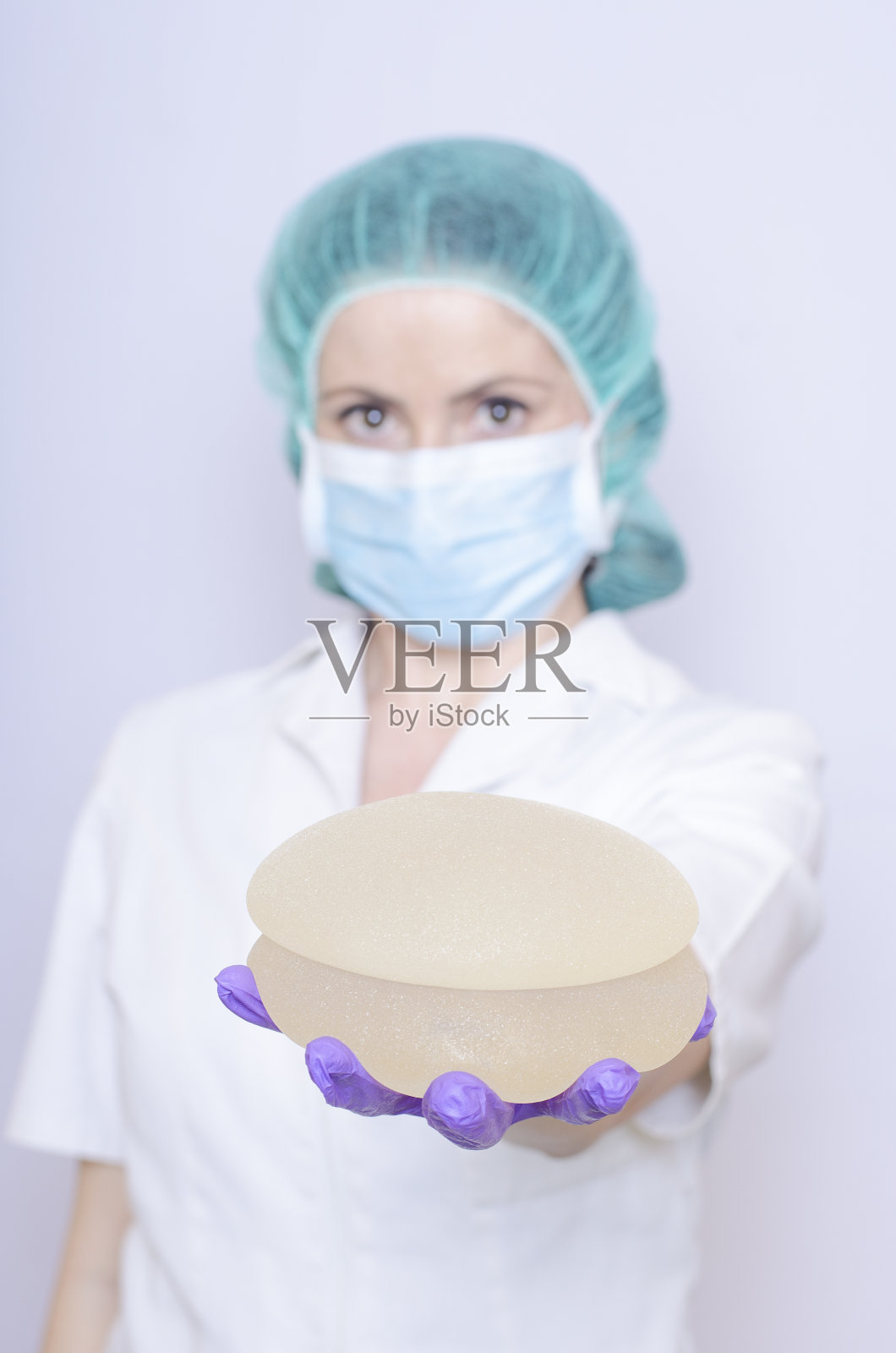 硅胶乳房植入手术。护士植入。医生拿着植入物照片摄影图片