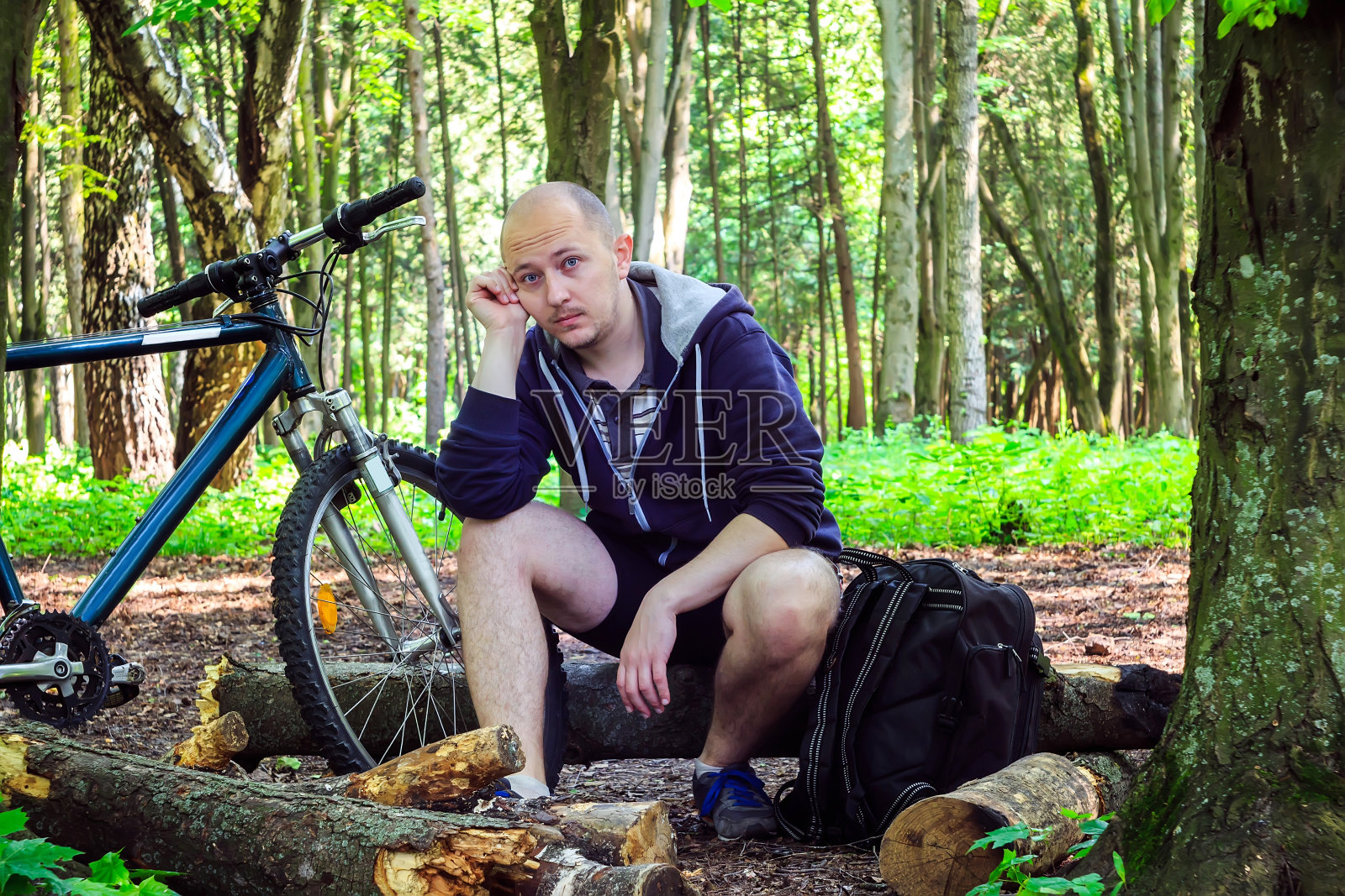 骑自行车的人背着背包，年轻人脸上带着疲惫在思考照片摄影图片