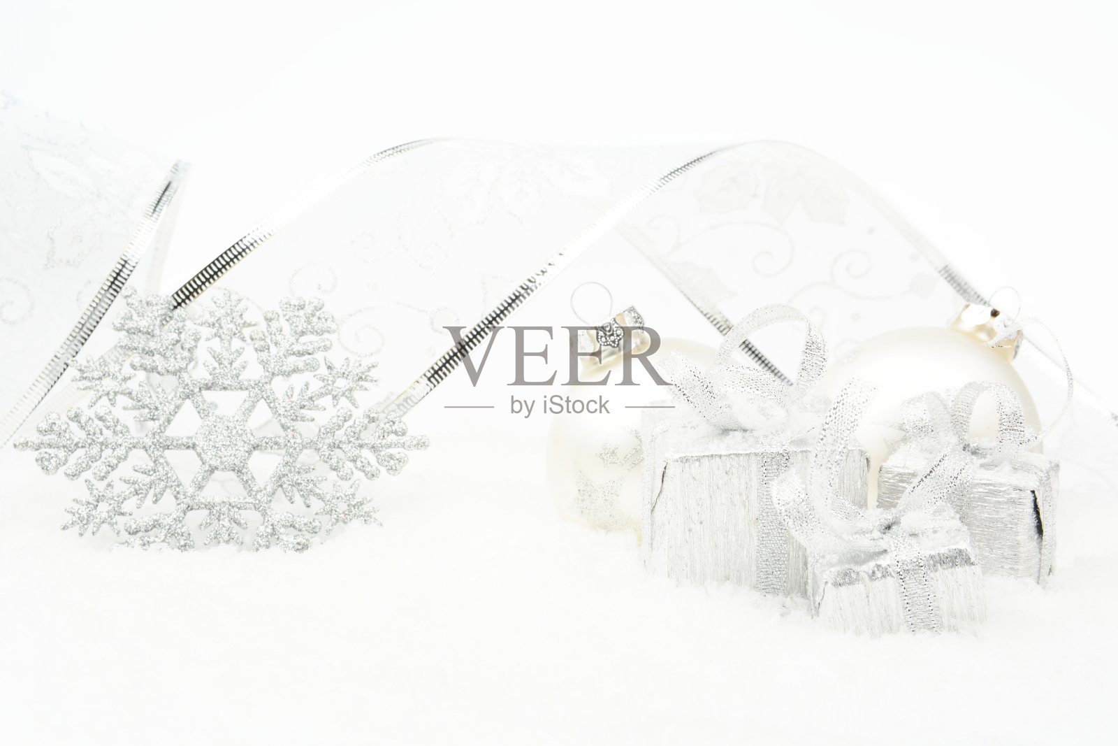 银色的圣诞装饰物，银白色的礼物，雪花上挂着银色的丝带照片摄影图片