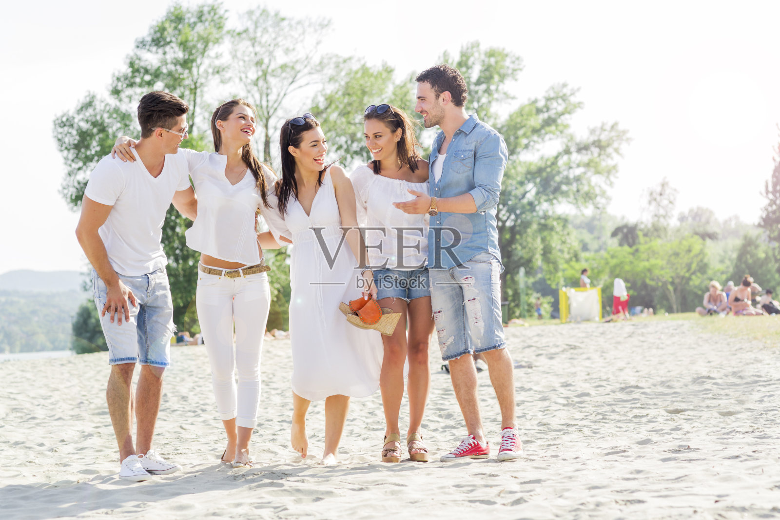 一群年轻人手牵着手在海滩上照片摄影图片