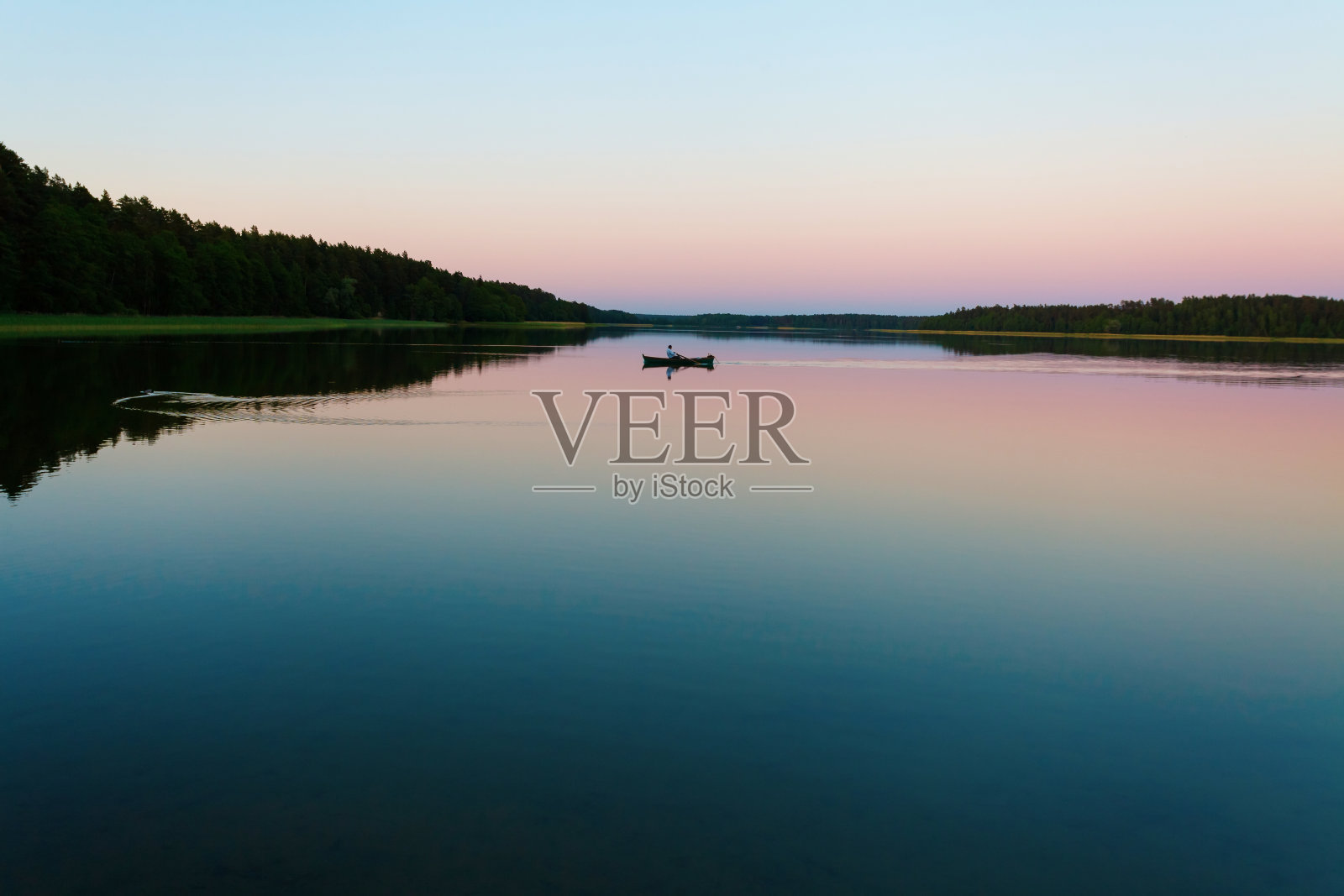 夕阳下平静湖面上孤独的小船照片摄影图片