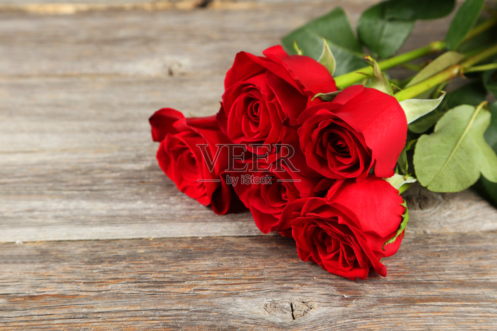 五朵新鲜的红玫瑰在灰色的木质背景上照片摄影图片