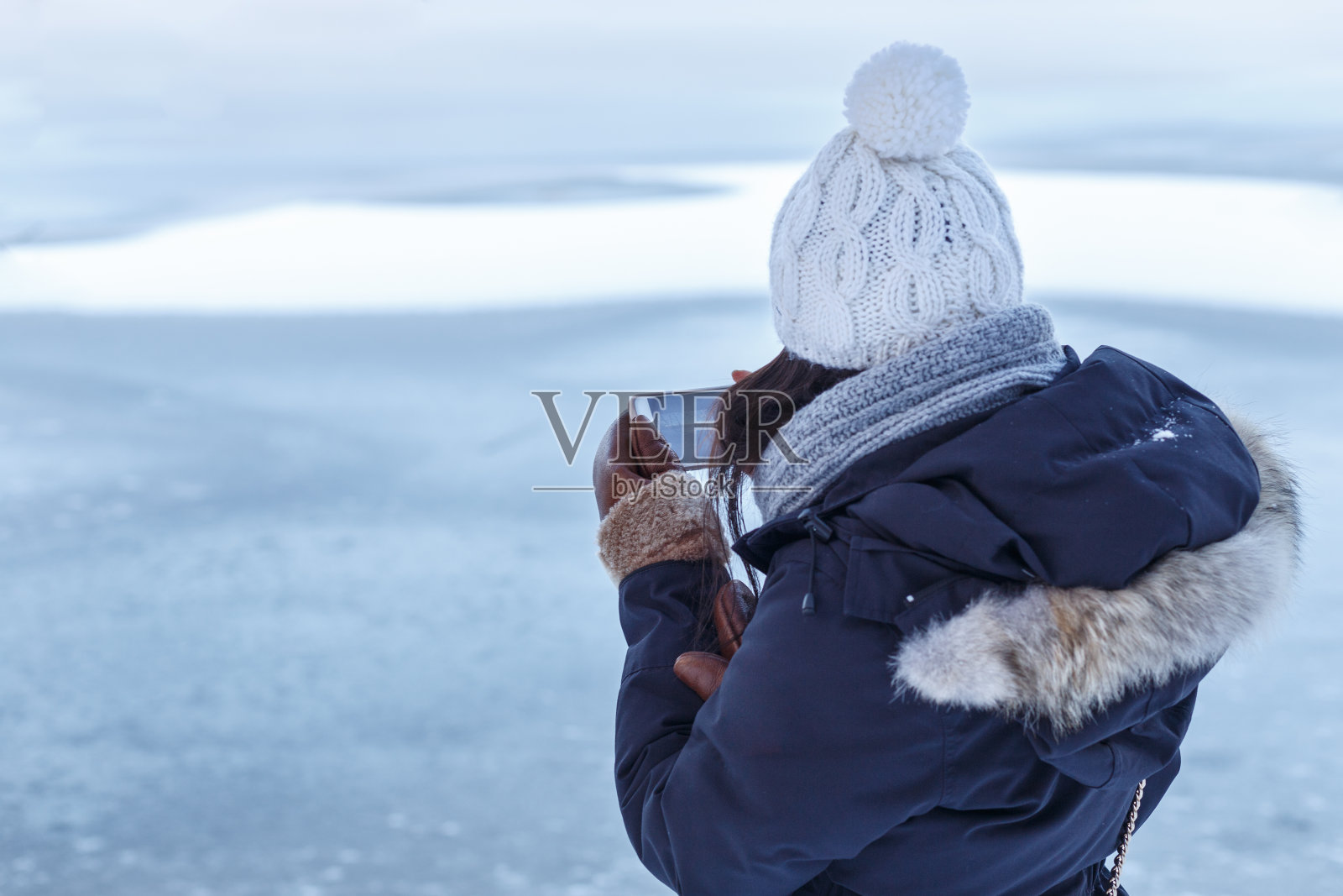 女孩在冬湖上查看照片照片摄影图片