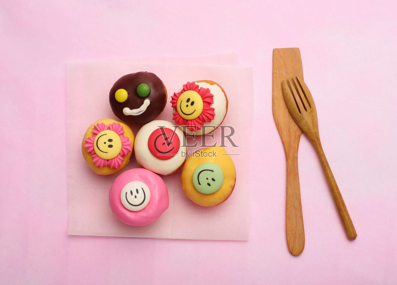 粉红色背景上的许多小纸杯蛋糕和木制工具照片摄影图片