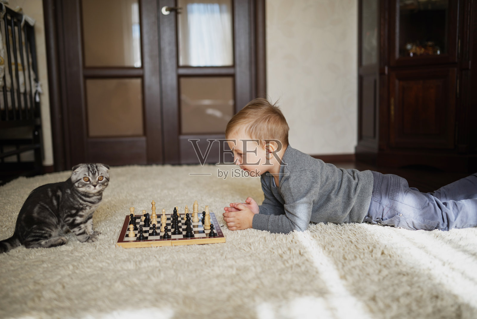小男孩躺在地板上下棋照片摄影图片
