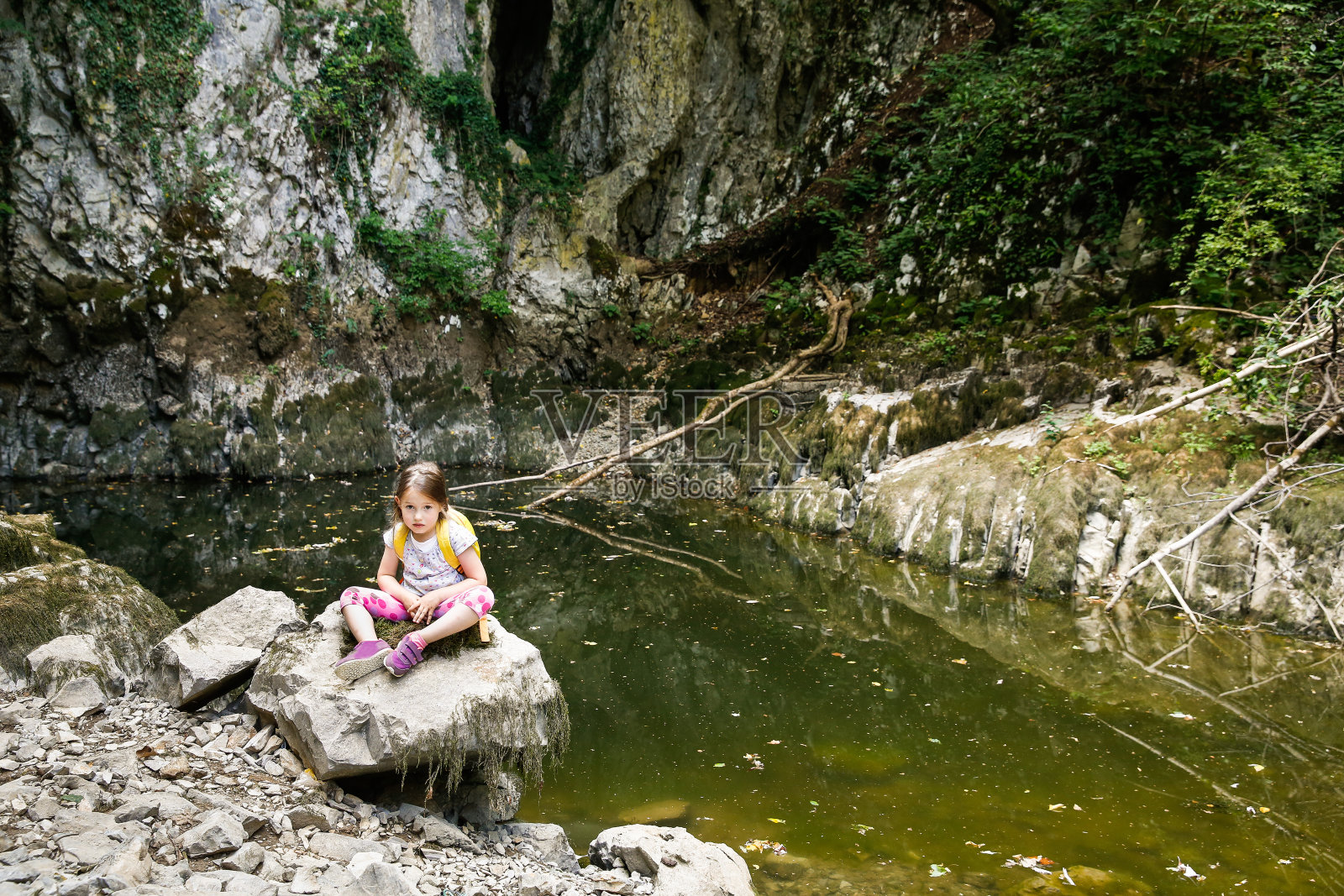 又累又烦的小女孩在一块大石头上休息照片摄影图片