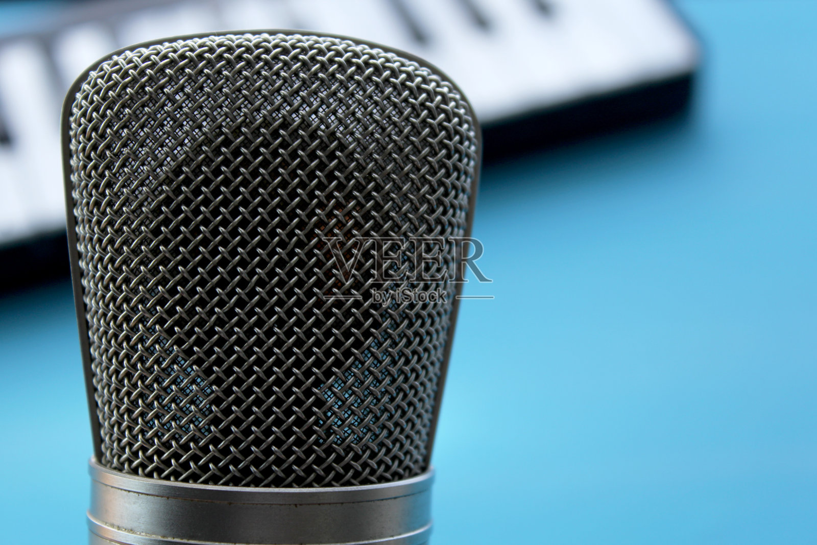 背景上有麦克风和模糊的钢琴键照片摄影图片