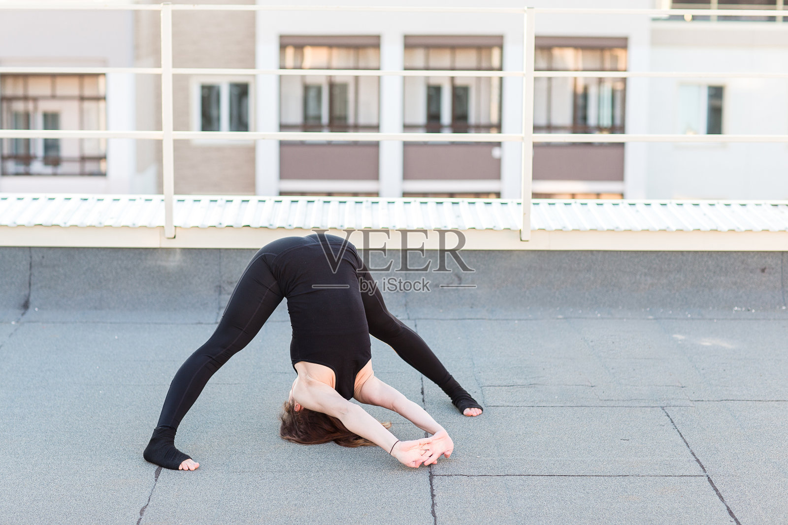 一个年轻女人在屋顶上做瑜伽照片摄影图片