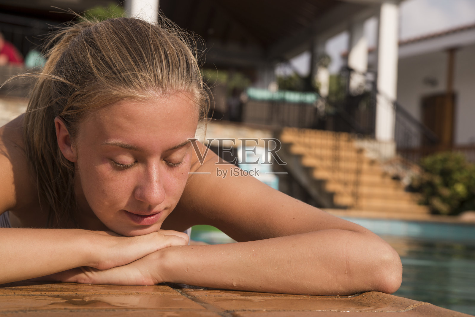 穿着泳衣的年轻女子躺在游泳池附近照片摄影图片