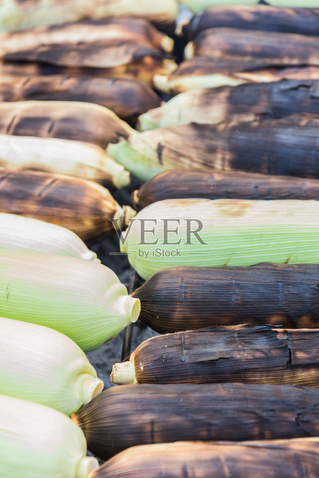 在木炭炉上烤甜玉米。敏感的焦点照片摄影图片